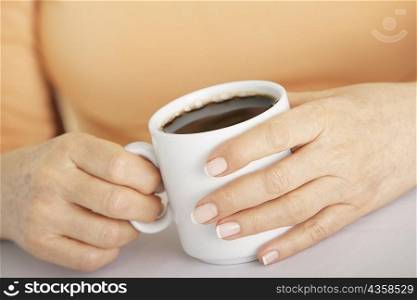 Mid section view of a woman&acute;s hand holding a cup of coffee