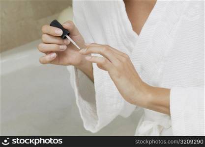 Mid section view of a woman applying nail polish on her fingernails