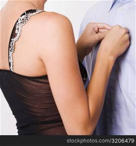 Mid section view of a woman buttoning the shirt of a man