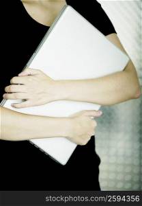 Mid section view of a woman carrying a laptop
