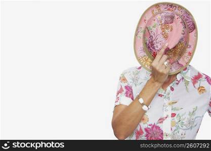 Mid section view of a woman covering her face with a fedora