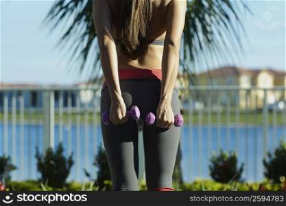 Mid section view of a woman exercising with dumbbells