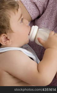Mid section view of a woman feeding her son with a baby bottle