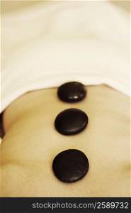 Mid section view of a woman getting hot stone therapy