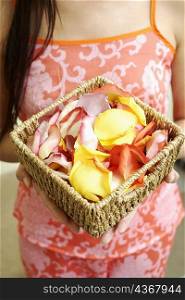 Mid section view of a woman holding a basket of flower petals
