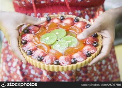Mid section view of a woman holding a fruit pie