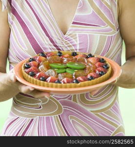 Mid section view of a woman holding a fruit tart