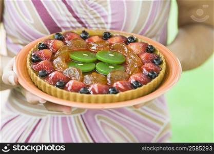 Mid section view of a woman holding a fruit tart