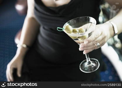 Mid section view of a woman holding a glass of cocktail