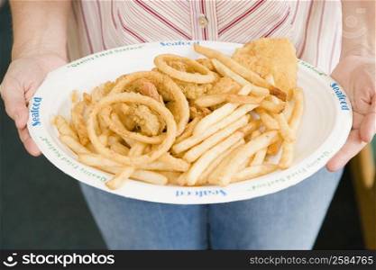 Mid section view of a woman holding a plate of snacks