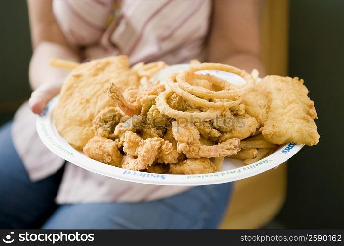 Mid section view of a woman holding a plate of snacks