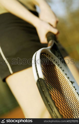 Mid section view of a woman holding a tennis racket