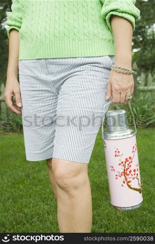 Mid section view of a woman holding an insulated drink container