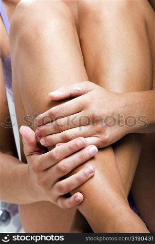 Mid section view of a woman holding her legs