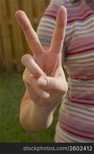 Mid section view of a woman making a peace sign