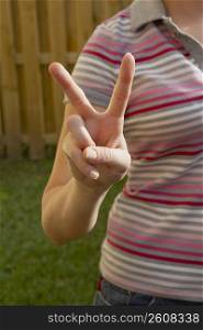 Mid section view of a woman making a peace sign