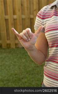 Mid section view of a woman making a shaka sign