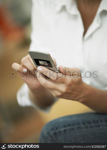 Mid section view of a woman operating a mobile phone