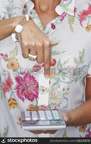 Mid section view of a woman pointing towards a calculator