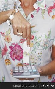 Mid section view of a woman pointing towards a calculator