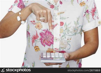 Mid section view of a woman pointing towards a calculator