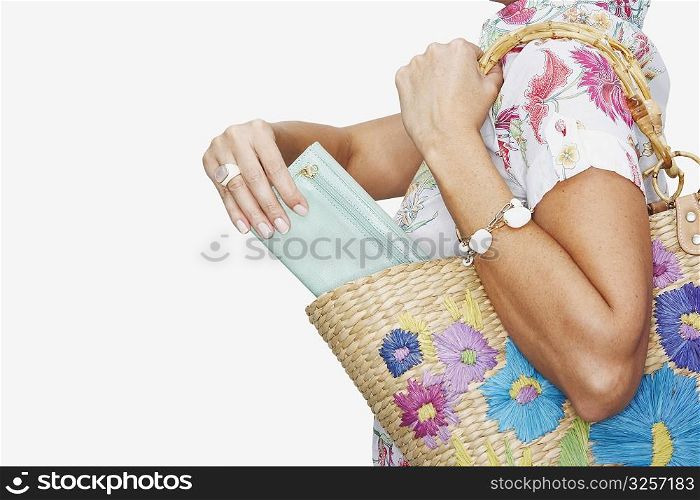 Mid section view of a woman putting a purse into a wicker basket