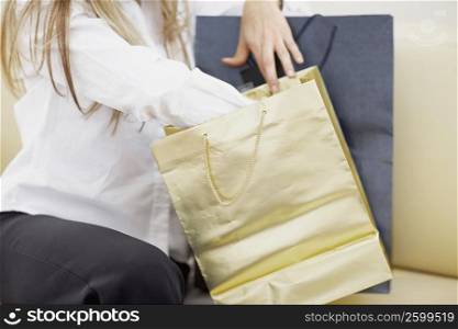 Mid section view of a woman sitting with shopping bags