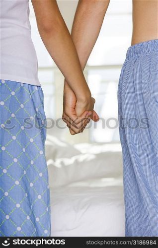 Mid section view of a young couple holding hands