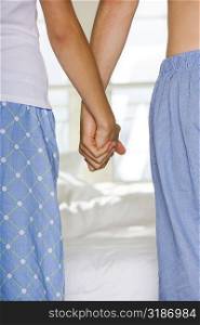 Mid section view of a young couple holding hands