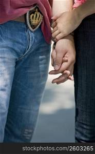 Mid section view of a young couple holding hands of each other