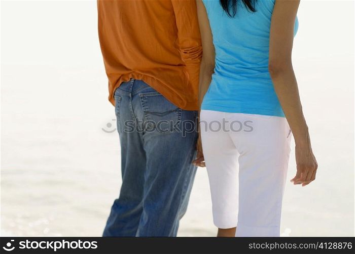 Mid section view of a young couple standing on the beach