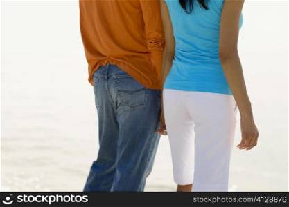 Mid section view of a young couple standing on the beach