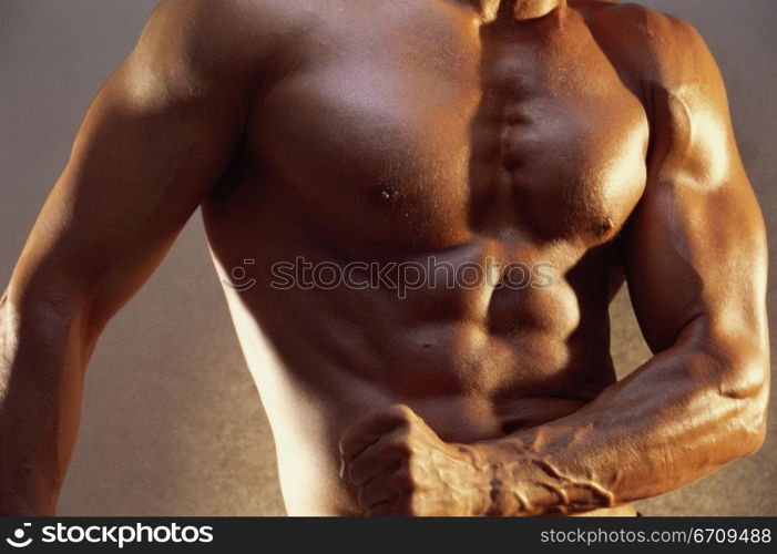 Mid section view of a young man flexing his muscles