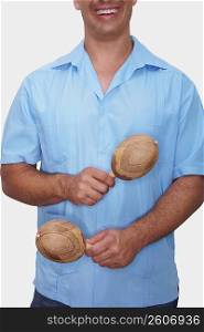 Mid section view of a young man holding a pair of maracas