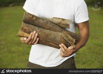 Mid section view of a young man holding firewood