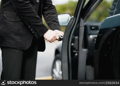 Mid section view of a young man opening a car door