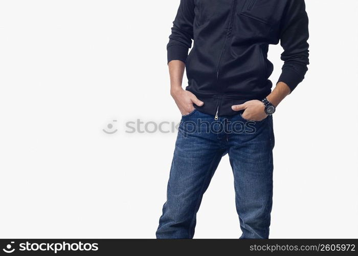 Mid section view of a young man standing with his hands in his pockets