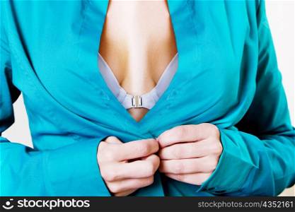 Mid section view of a young woman buttoning her shirt