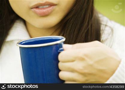 Mid section view of a young woman holding a cup of coffee