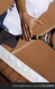 Mid section view of a young woman holding a tennis racket and reaching out for a handshake