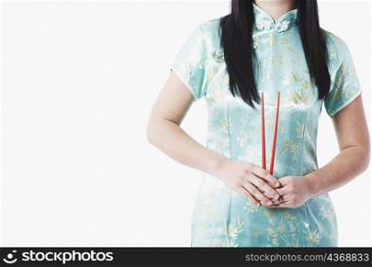 Mid section view of a young woman holding chopsticks