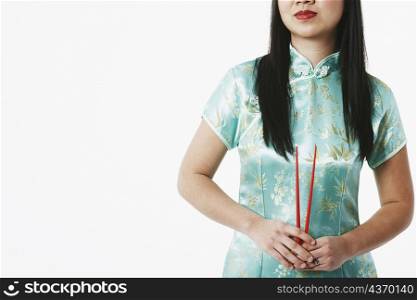 Mid section view of a young woman holding chopsticks
