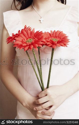 Mid section view of a young woman holding flowers
