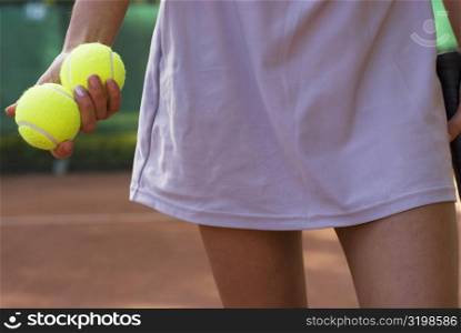 Mid section view of a young woman holding two tennis balls