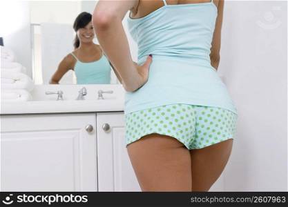 Mid section view of a young woman looking at the mirror