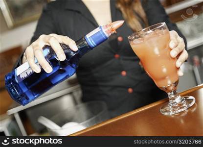 Mid section view of a young woman making a cocktail