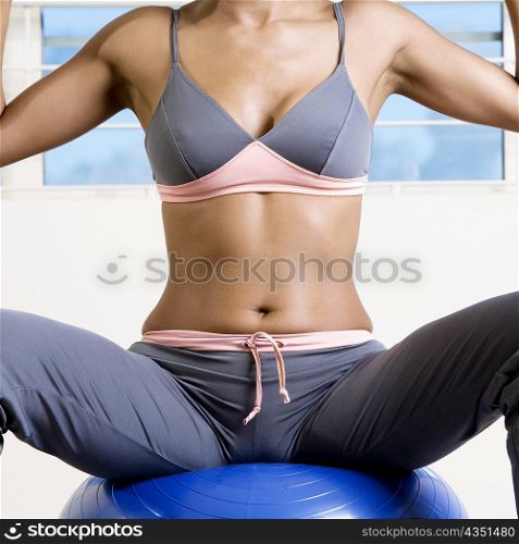 Mid section view of a young woman sitting on a fitness ball