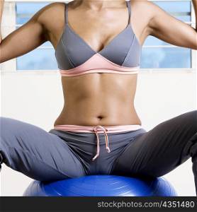 Mid section view of a young woman sitting on a fitness ball
