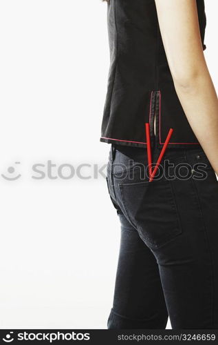 Mid section view of a young woman with chopsticks in her pockets