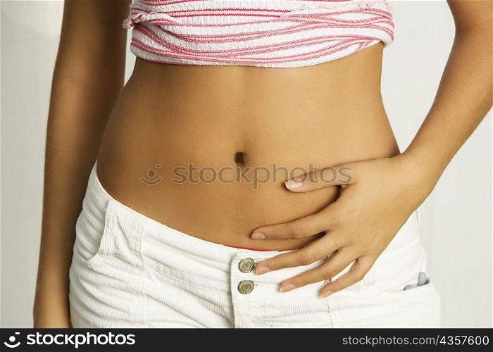 Mid section view of a young woman with her hands on her stomach